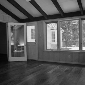 A photograph of an empty room, with the photographer's reflection in the glass pane of the door